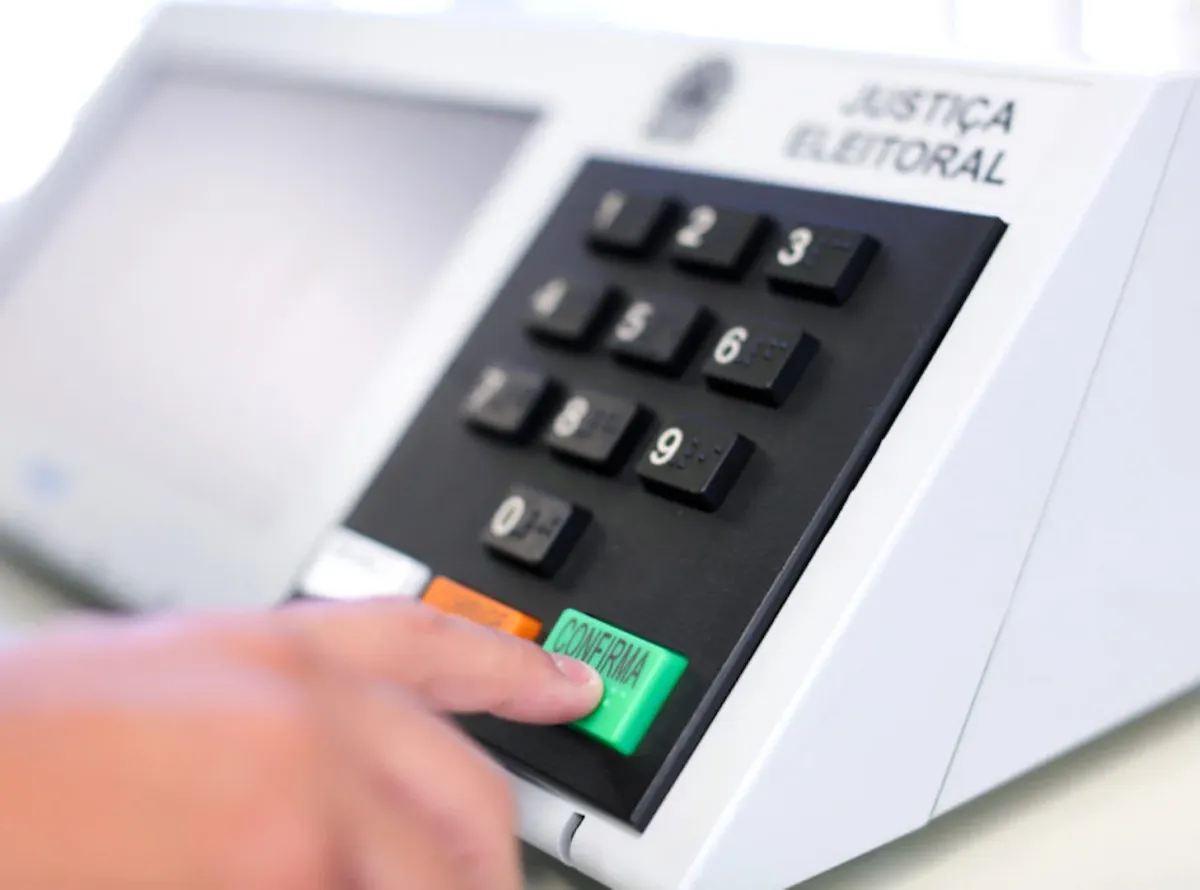 Eleitor segurando celular com o aplicativo e-Título aberto para consulta de local de votação.