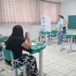 Eleitor na cabine de votação com urna eletrônica em destaque