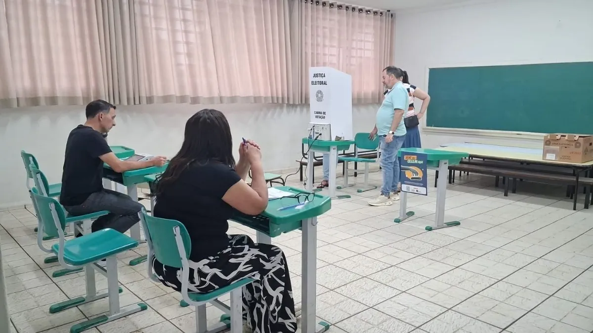 Eleitor na cabine de votação com urna eletrônica em destaque