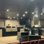 Urna eletrônica em seção eleitoral com eleitor votando.