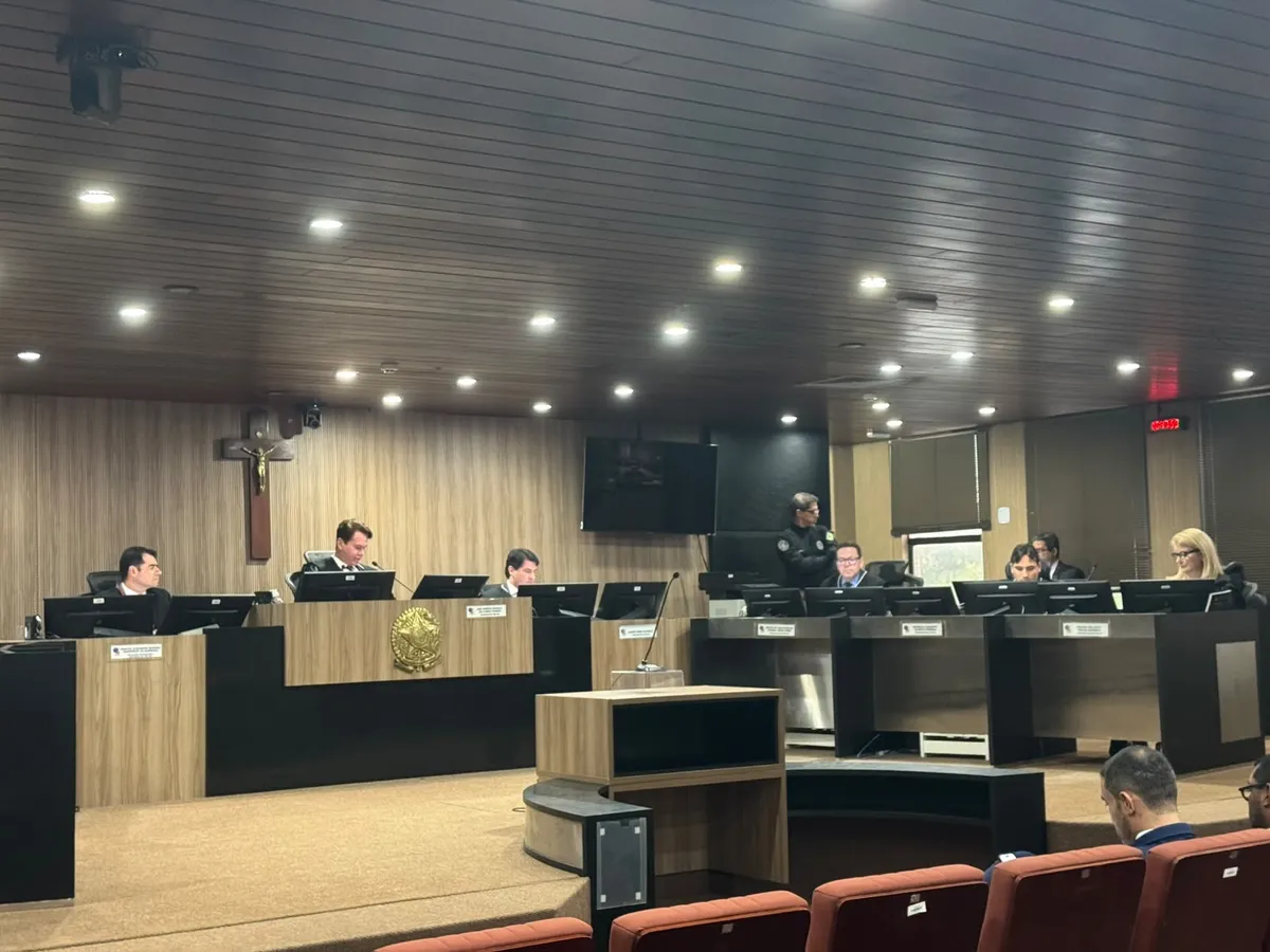 Urna eletrônica em seção eleitoral com eleitor votando.